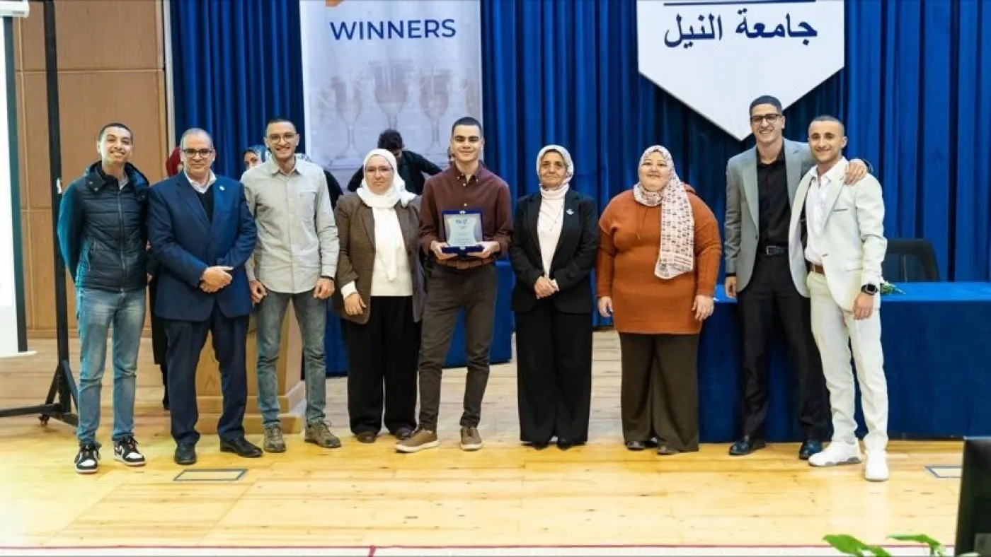 A line of students and faculty on stage beneath a "winners" board